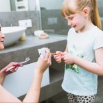 Майка слага паста за зъби на четката на детето си