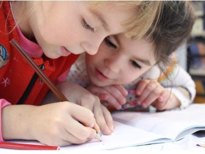 Две деца рисуват в тетрадка.