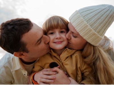 майка и баща целуват детето си