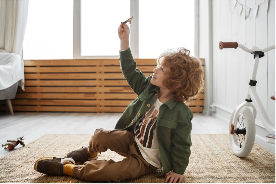 Момче си играе с играчка в светла детска стая