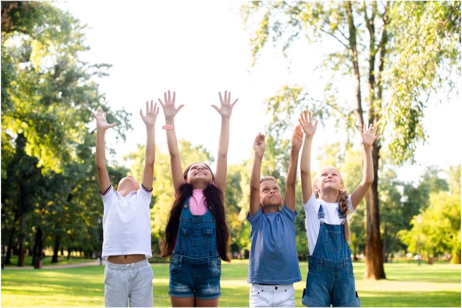 Група деца на поляна с вдигнати ръце